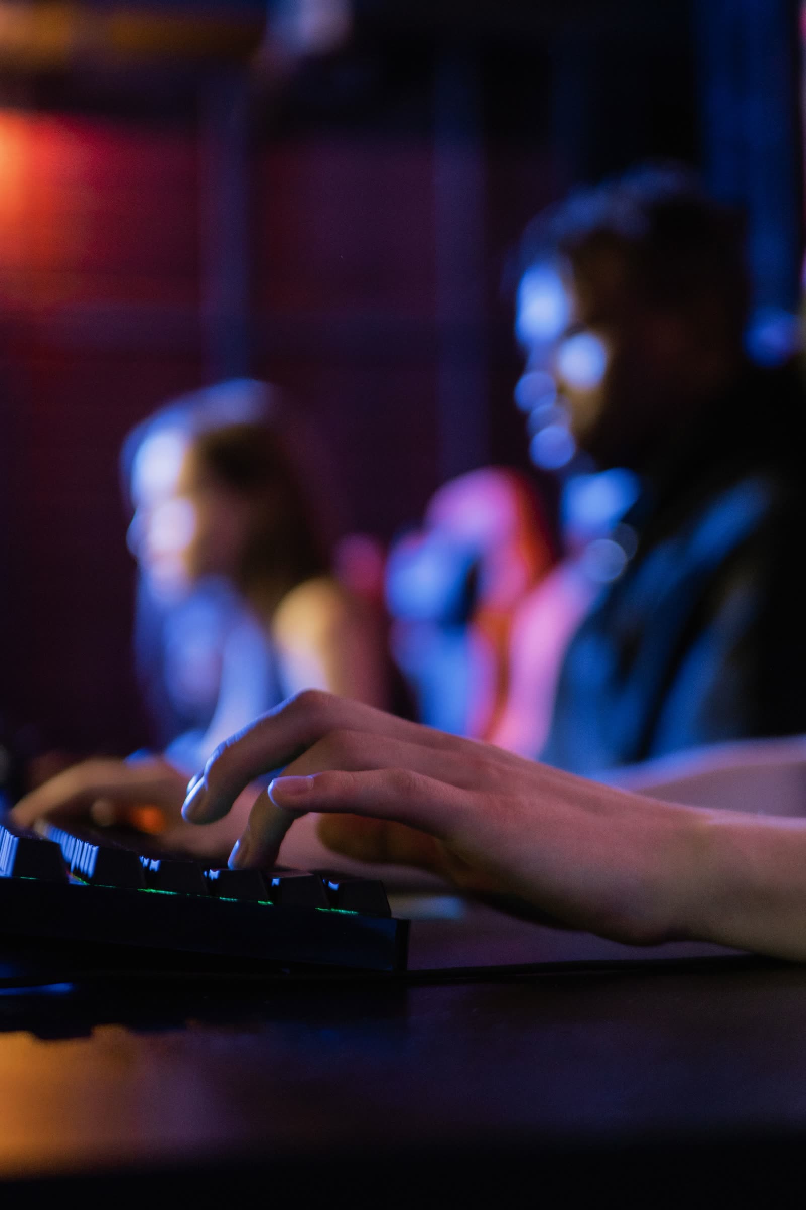 Close-up of a player's hands on a backlit mechanical keyboard at a NOPING tournament seat